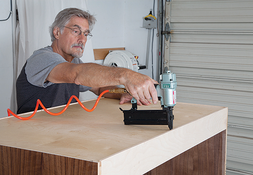 Using nail gun to secure back panel onto vanity