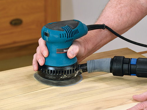 Smoothing out a strip of wood with a random orbit sander