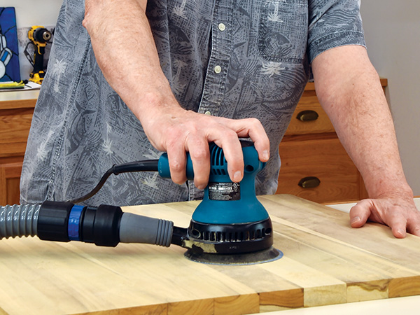 Sanding a wood panel with random orbit sander