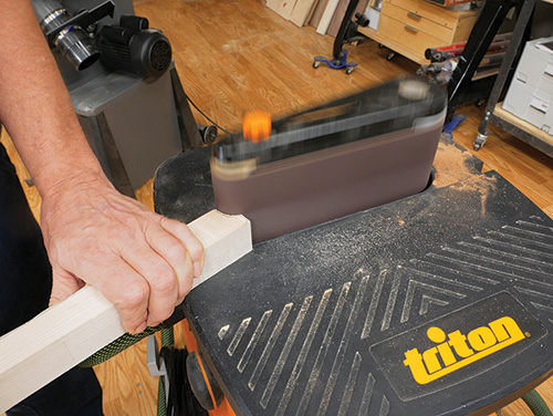 Smoothing out end of of table leg with belt sander