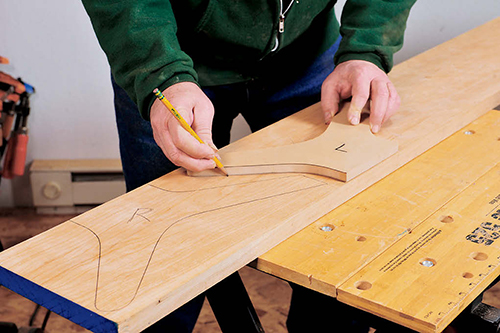 The table's MDF leg template is used to lay out alternating right- and left-hand legs on a 5/4 cherry board.