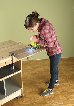 Two large rectangular sections are cut out of the lower two laminations of the shelf. Use a handheld jigsaw to remove the material.