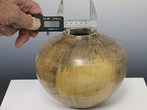 Checking the measurements of the inside of a vase's mouth