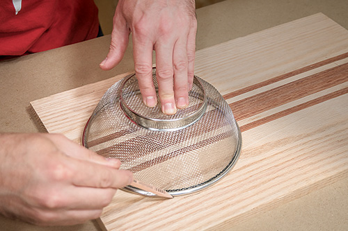 Tracing strainer outline on over the sink cutting board project