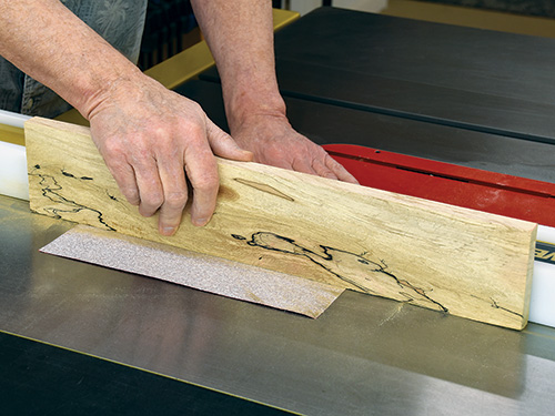 Sanding a board using sandpaper fixed to the table saw fence