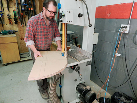 Use either a band saw or a jigsaw to rough-cut the arc and then sand carefully to your line to fair the curve.