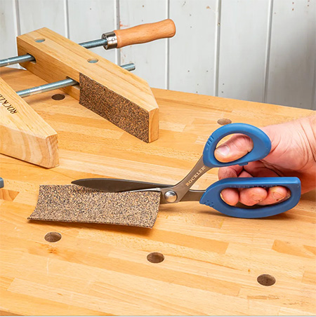 Cutting sandpaper with workshop scissors