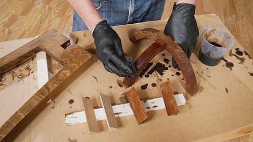 Applying mission oak dye to center support pieces of plant stand