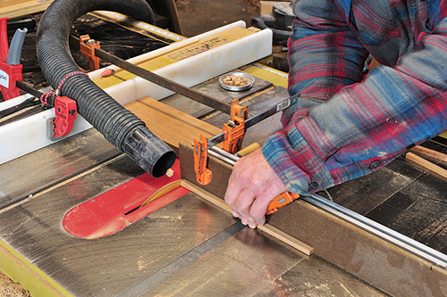 A shop vacuum hose nozzle, clamped atop the saw table, collects the small spacer blocks as they are cut, thus preventing them from being flung by the blade and lost.