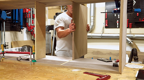 Putting vertical partition in place in walnut storage cabinet